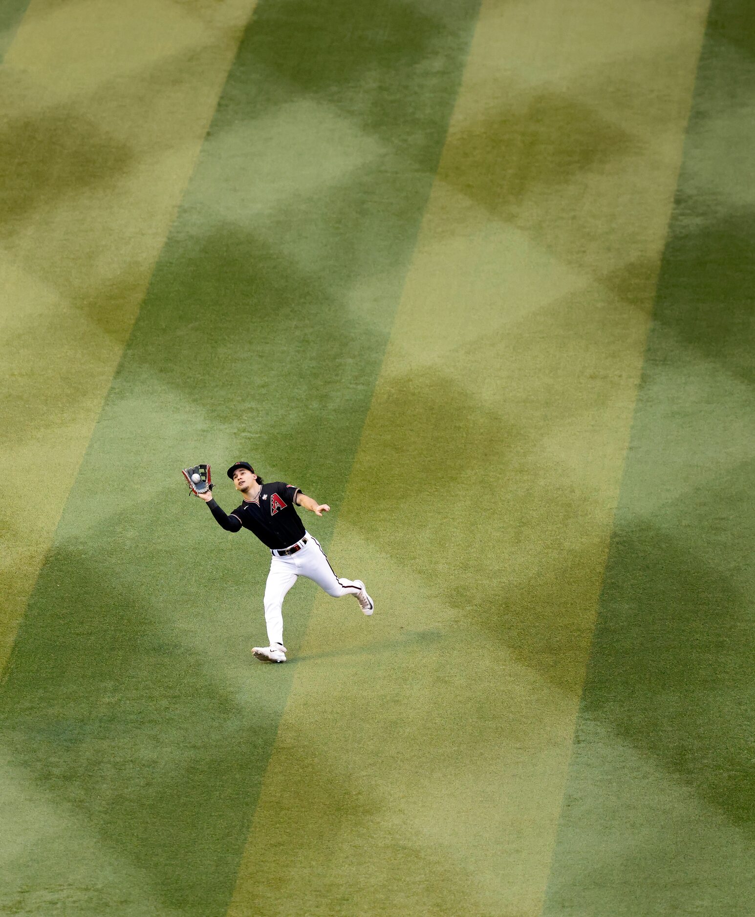 Arizona Diamondbacks center fielder Alek Thomas (5) charges in catching a fly out by Texas...