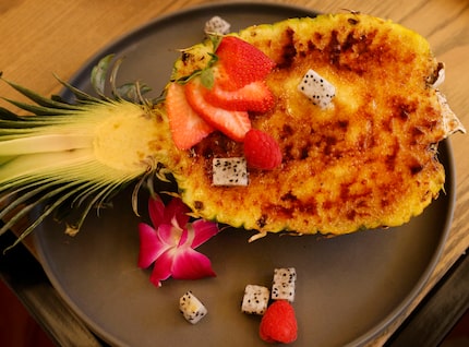 A dessert of piña colada crème brûlée is served inside a cored-out half pineapple.