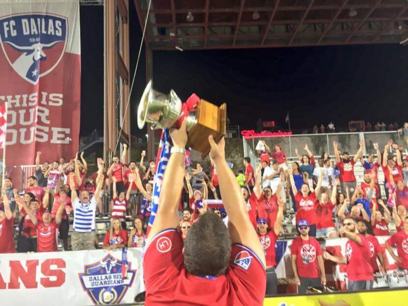 FC Dallas fan, Andre Dobbs, holds the Brimstone Cup aloft in front of the Dallas Beer...