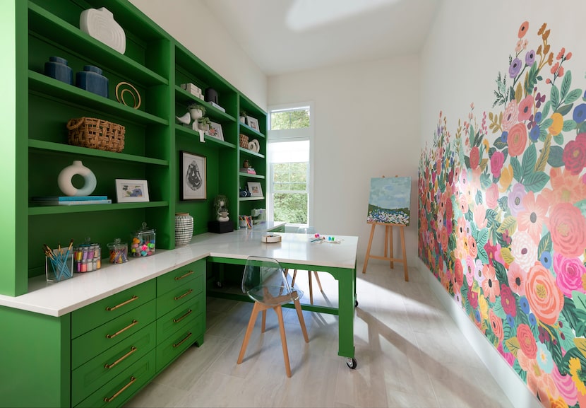 Craft and play room with green bookshelves and a floral mural