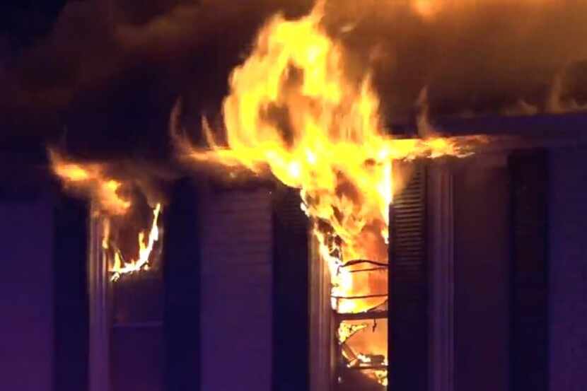 Flames shoot through windows at a northwest Dallas apartment complex. About 30 residents...