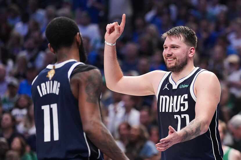 Dallas Mavericks guard Luka Doncic laughs with guard Kyrie Irving (11) after being called...