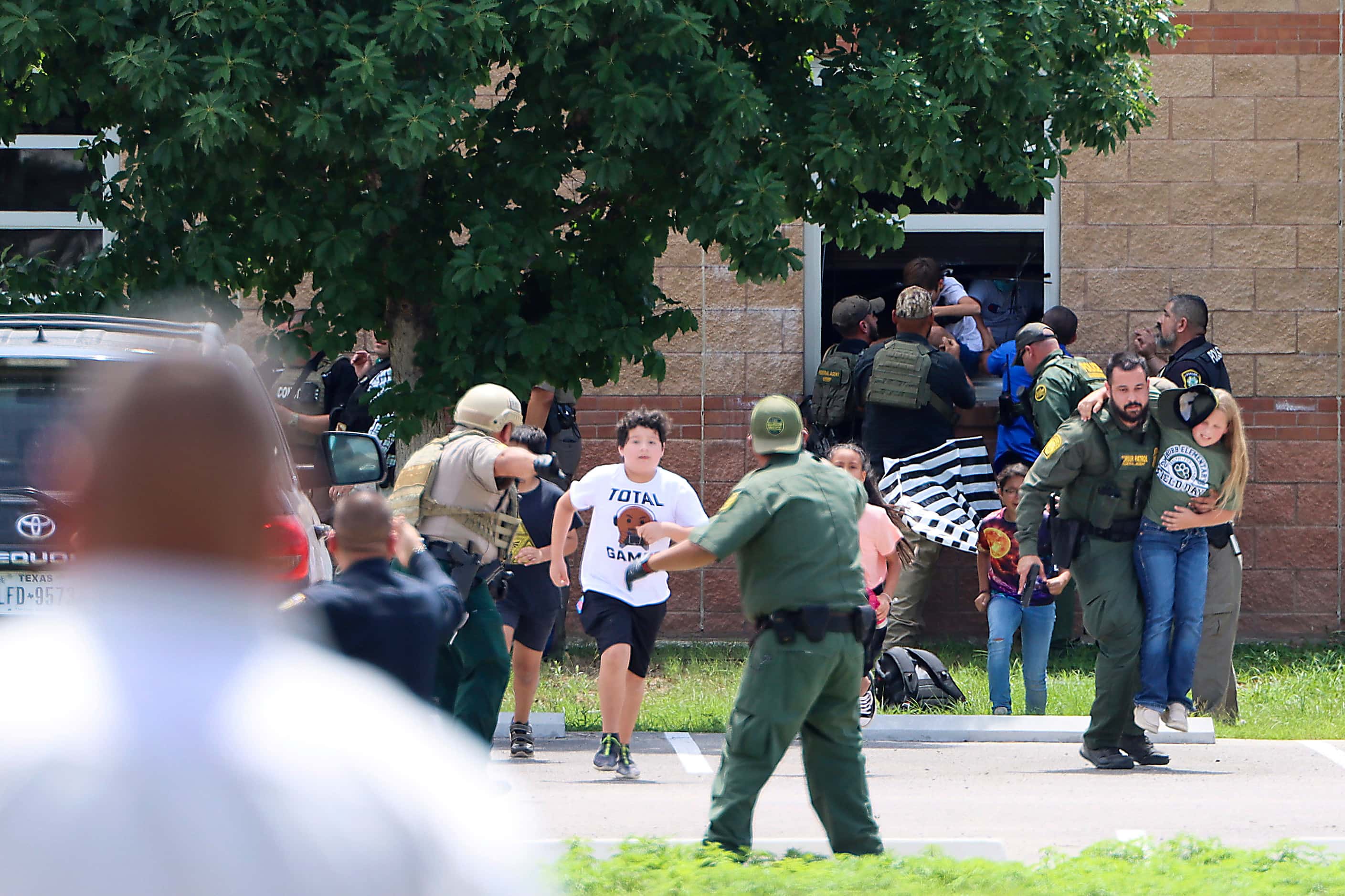 School children are evacuated by law enforcement officers through classroom windows in a...