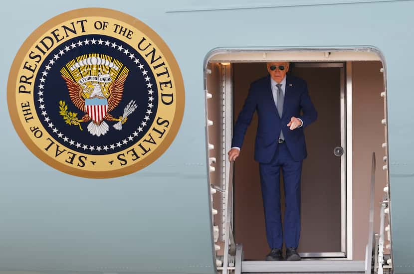 President Joe Biden gestures before walking down the steps of Air Force One upon arrival at...