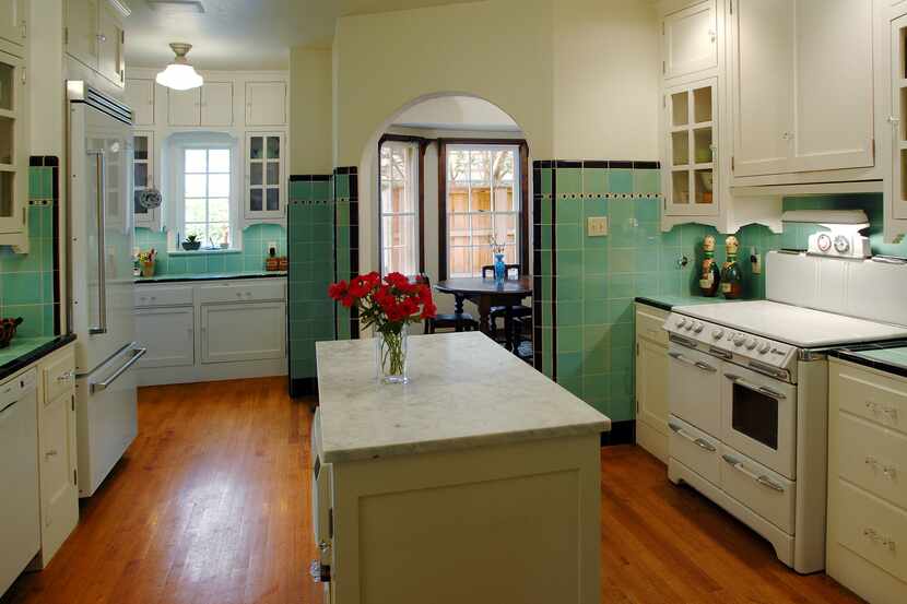 A kitchen is lined with green and black tile, offering a vintage look. Upper and lower...