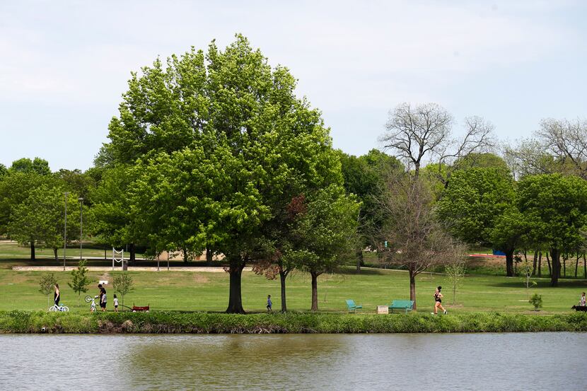 People make their way around a pond at Bob Woodruff Park in Plano, Texas on Tuesday, April...