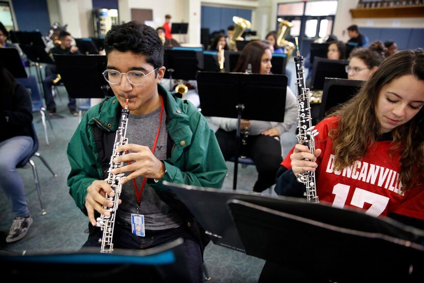 Freshman oboe player David Mojica (left) warms up on his instrument alongside classmate...