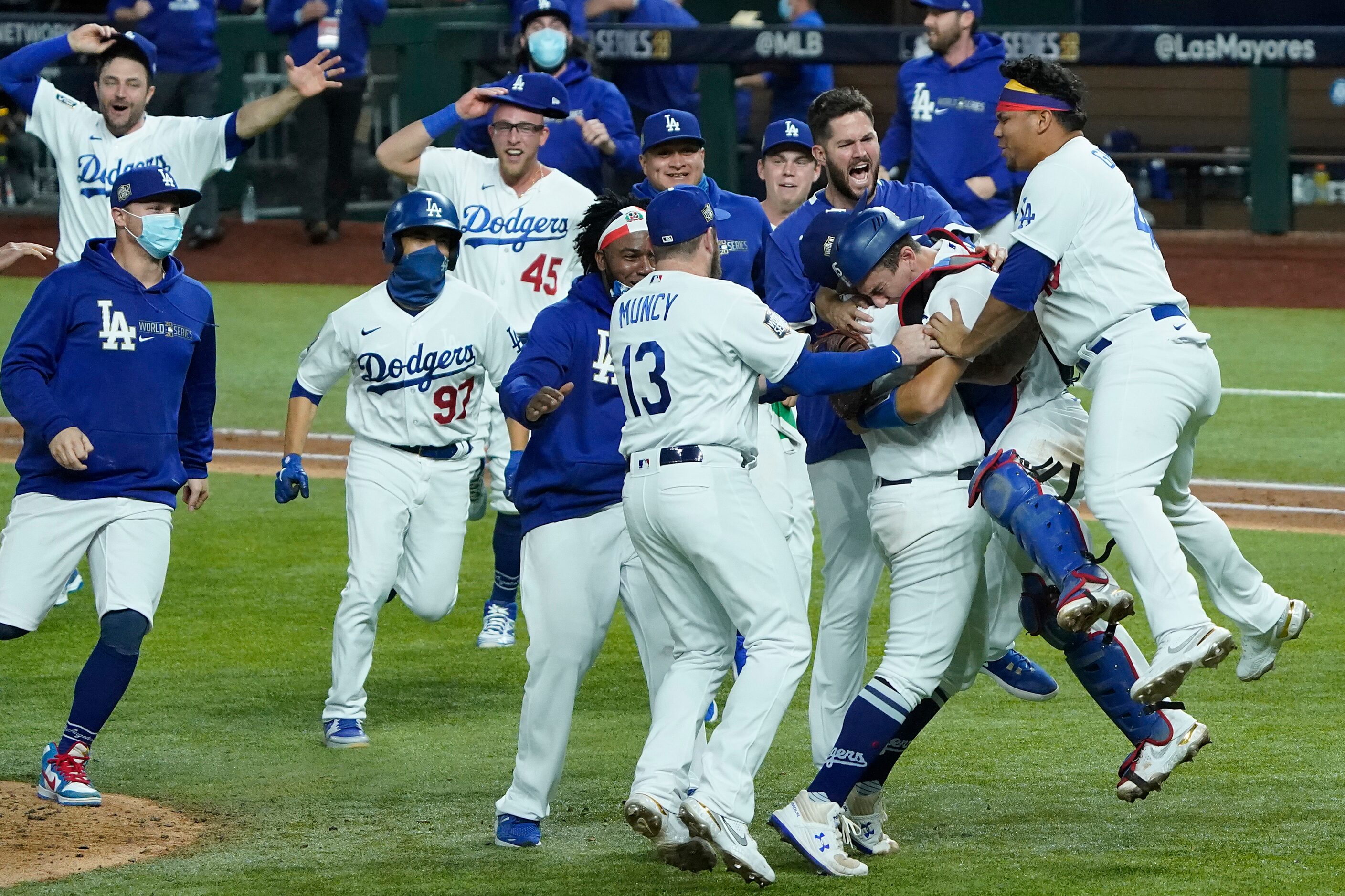 Los Angeles Dodgers players rush to join pitcher Julio Urias and catcher Austin Barnes as...