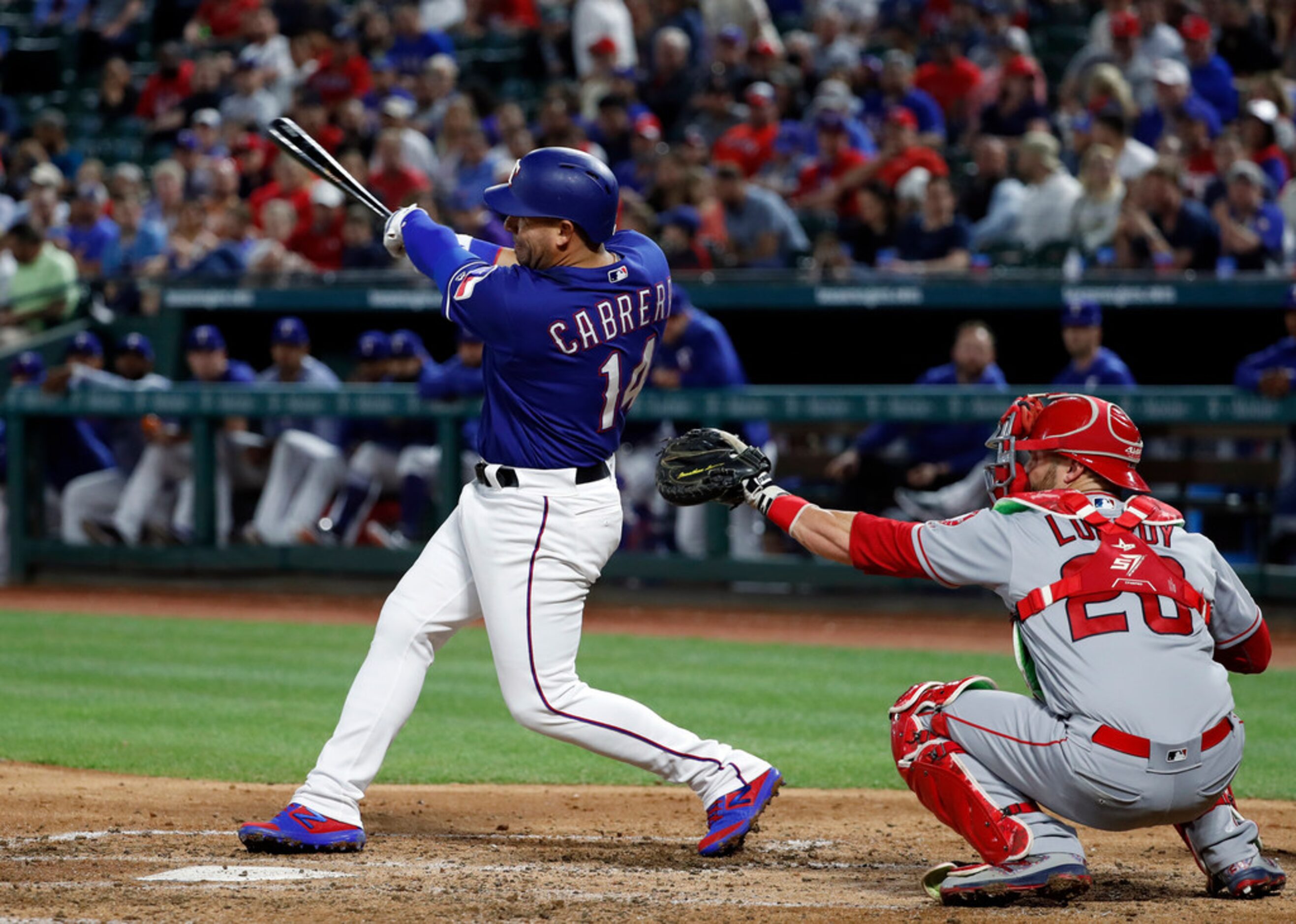 Texas Rangers' Asdrubal Cabrera follows through on a two-run home run in front of Los...