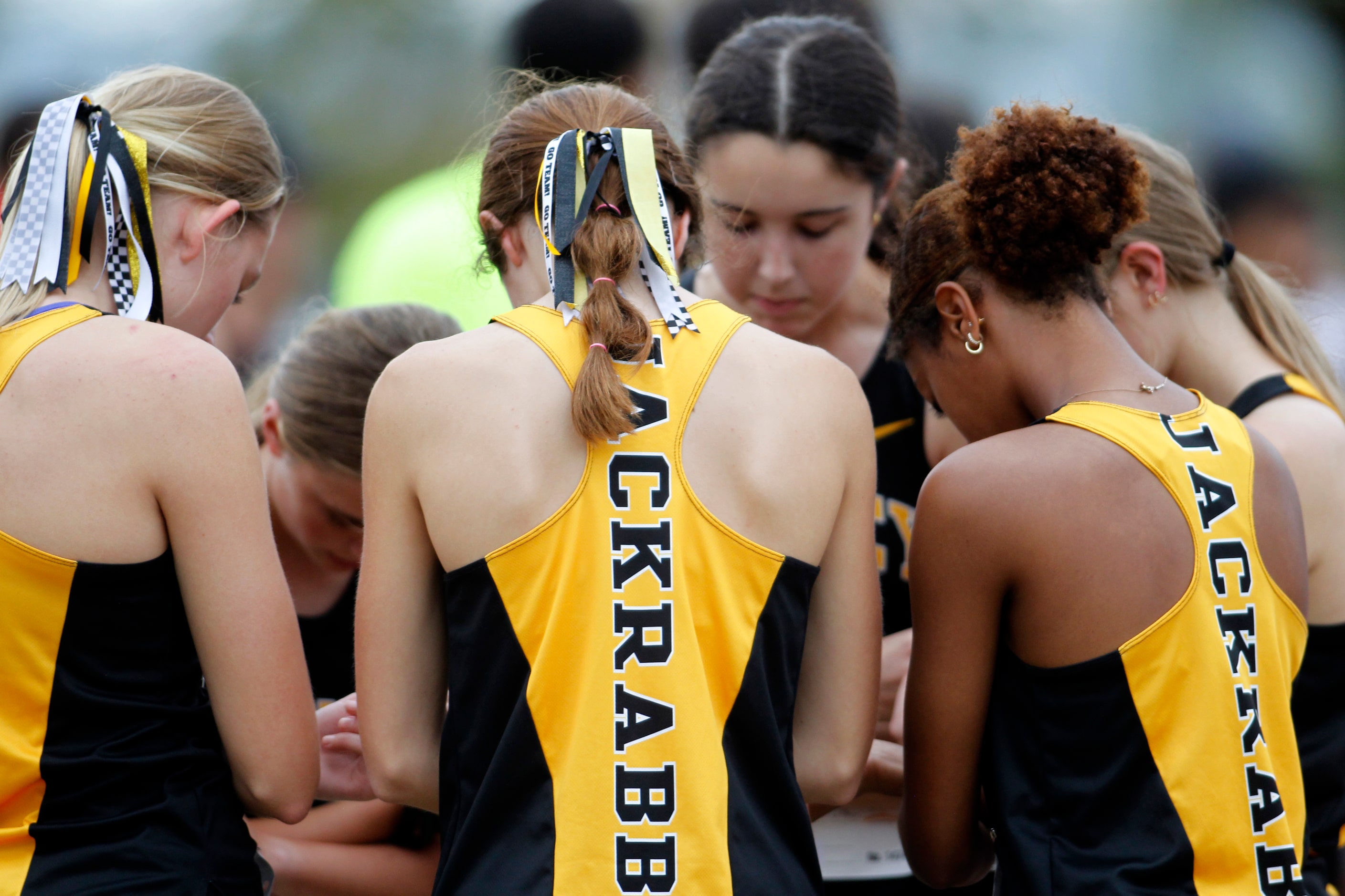 Members of the Forney Jackrabbits girls cross country team pause to pray before the start of...