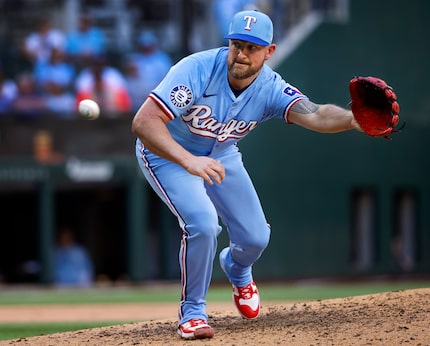 Texas Rangers relief pitcher Kirby Yates (39) fields an infield hit by Los Angeles Angels...