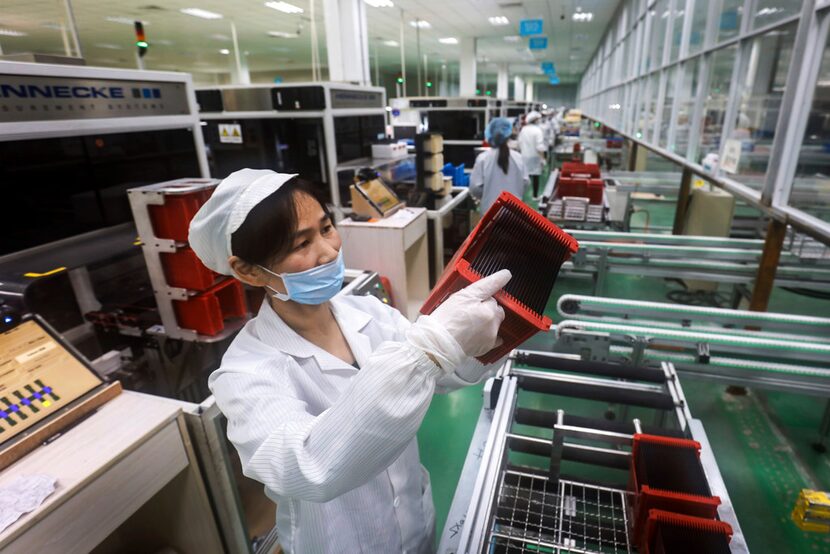 In this March 16, 2018, photo, a worker checks solar panels at a factory in Jiujiang in...