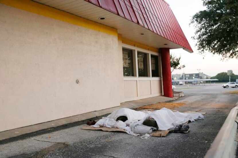 
Two homeless men sleep in the driveway of a closed payday loan store on East Northwest...