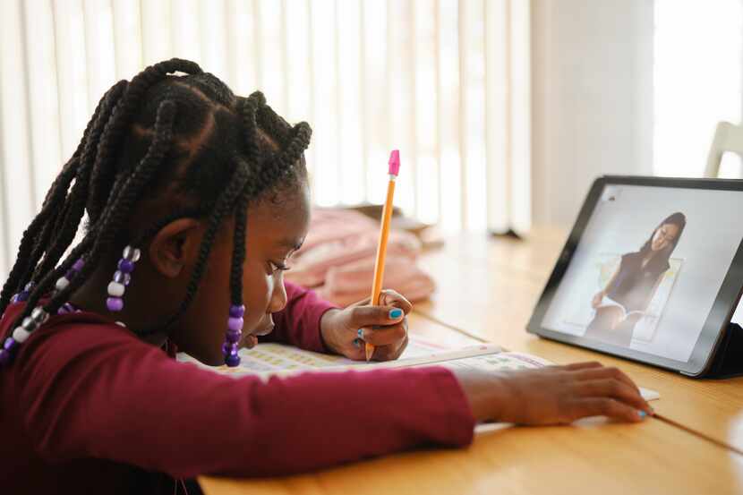 An elementary aged school student in a home doing remote learning.