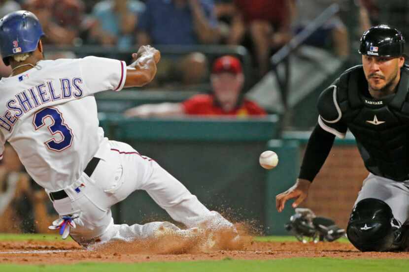 Texas Rangers left fielder Delino DeShields (3) slides home safely as he scores on a...