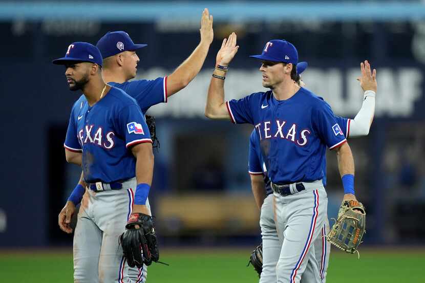 Texas Rangers left fielder Evan Carter, front right, and teammate Nathaniel Lowe, back left,...