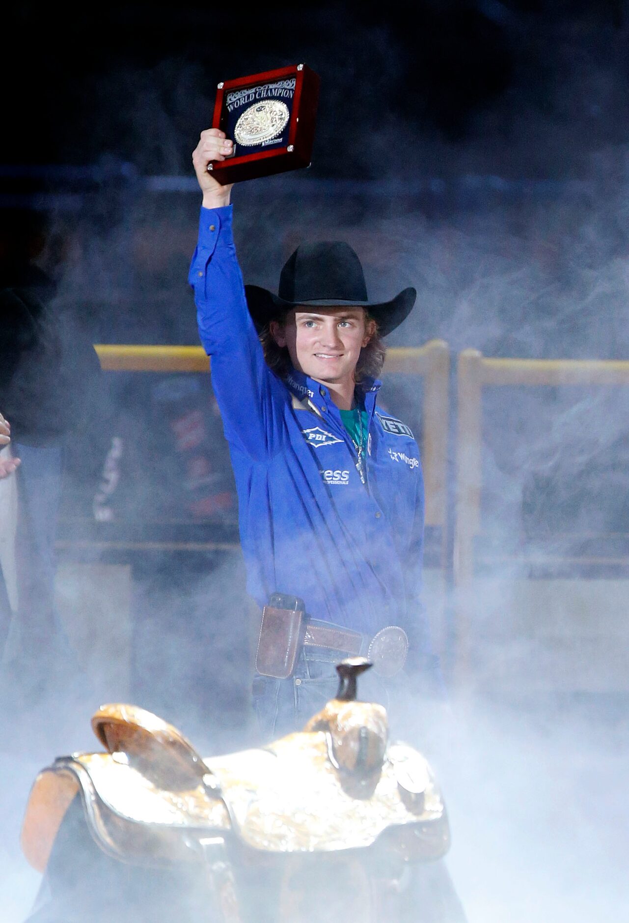 Saddle Bronc Champion Ryder Wright of Milford, Utah raises his winning belt buckle during...