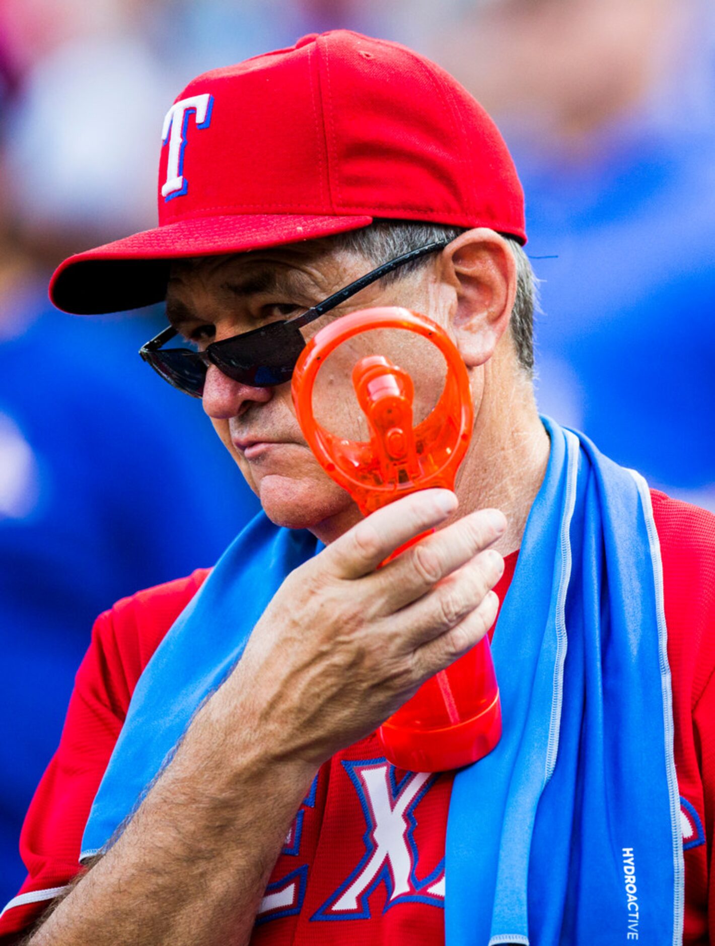 A Rangers fan sprays himself with a portable fan before an MLB game between the Texas...