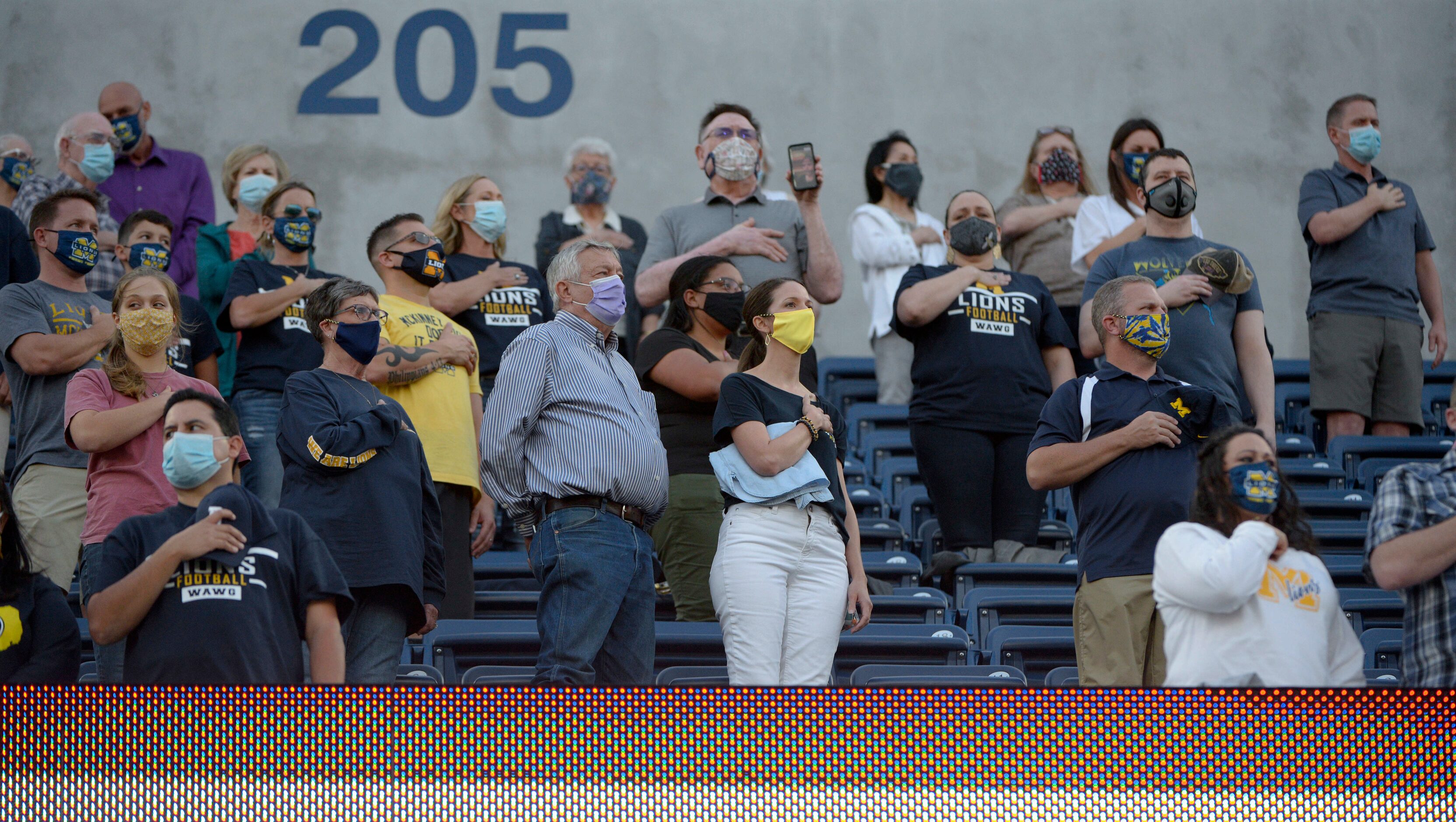 Football fans stand for the National Anthem before a high school football game between Plano...