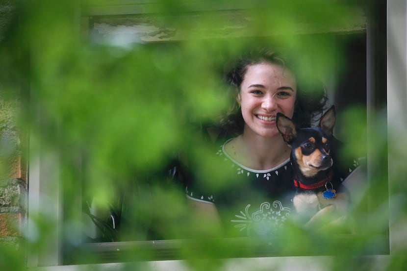Erinn Sensenig poses for a photograph with her dog Ollie in the window of her Dallas...