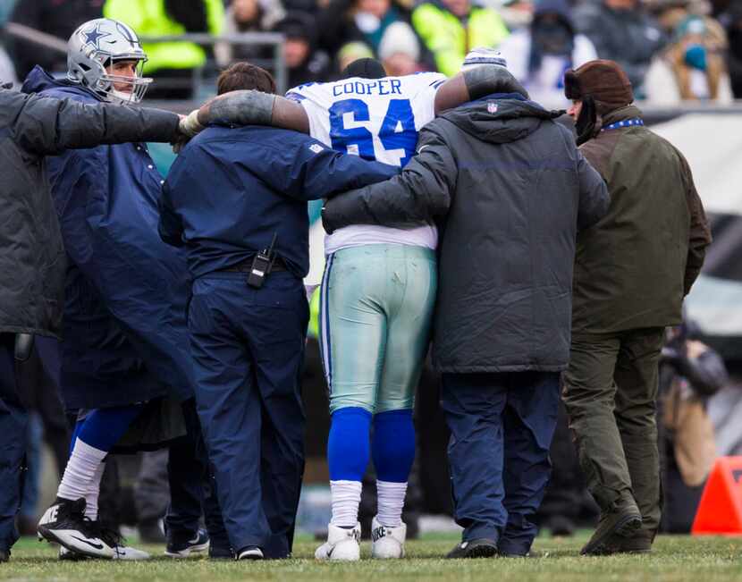Dallas Cowboys offensive guard Jonathan Cooper (64) is helped off the field during the...