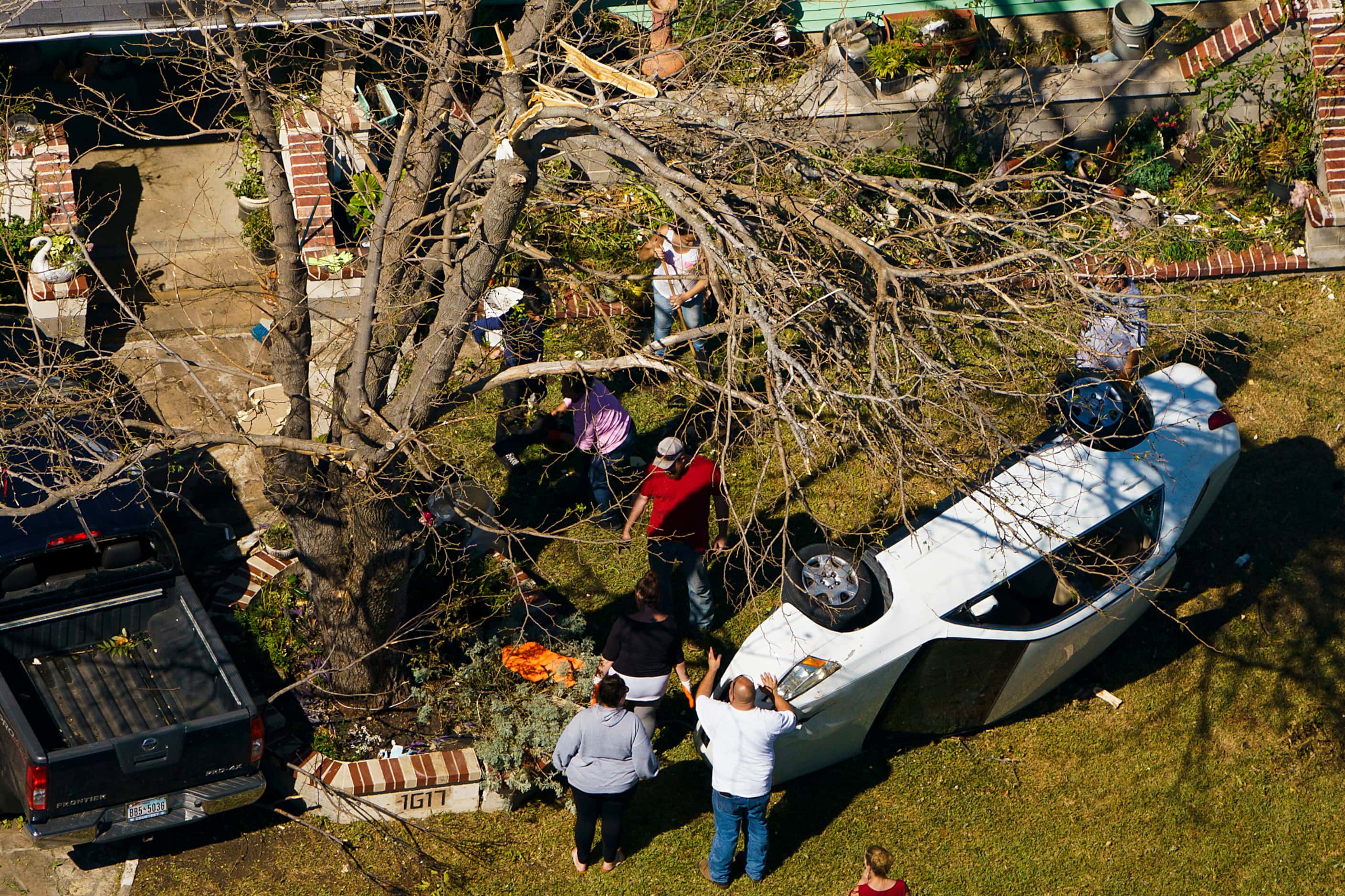 People survey an upturned automobile in the front yard of a home on Monday, Oct. 21, 2019,...
