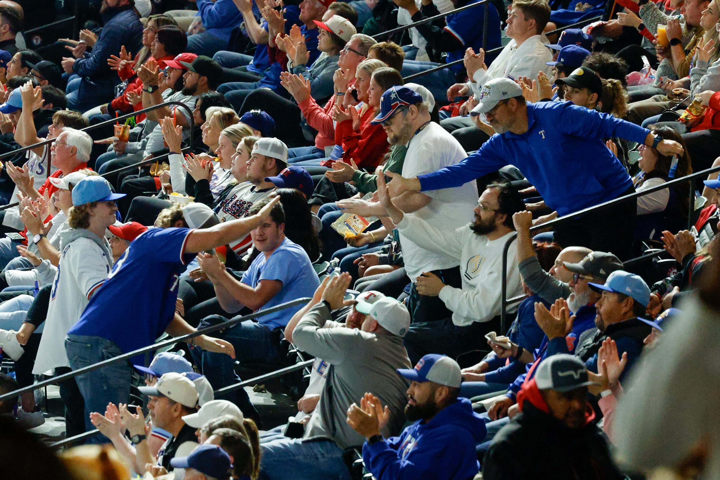 Fans cheer after an inning-ending double play by the Texas Rangers during the first inning...