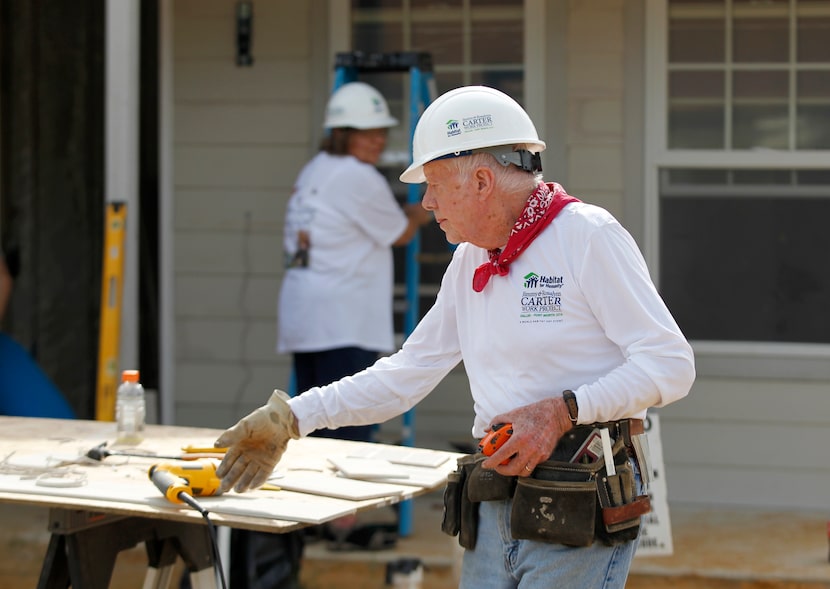 Former President Jimmy Carter, then age 90, works on siding for a Habitat for Humanity house...