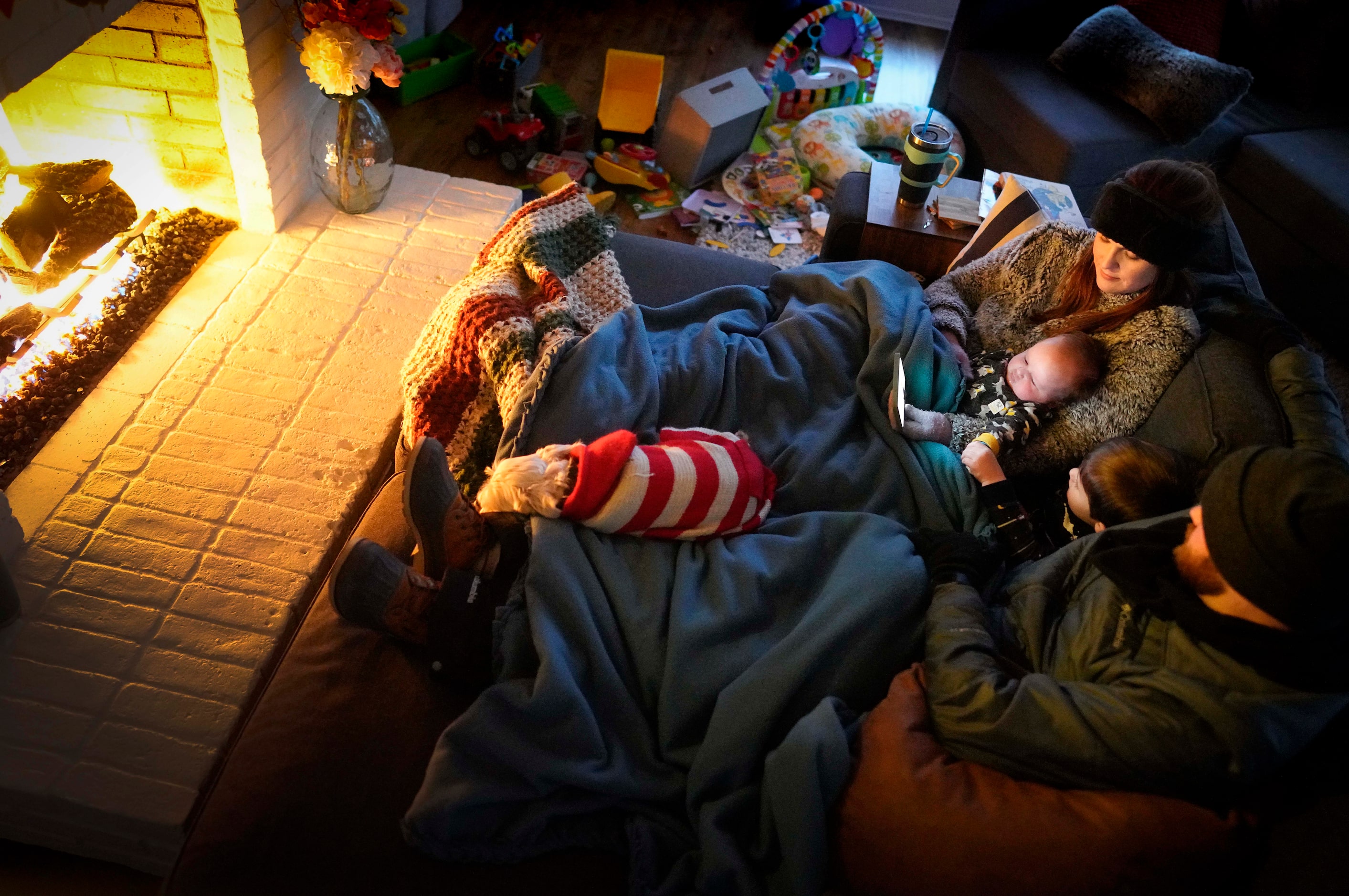 Dan Bryant and his wife Anna huddle by the fire with sons Benny, 3, and Sam, 12 weeks, along...