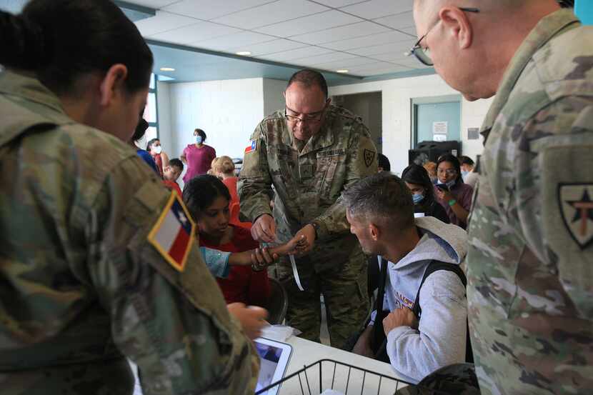 An officer from the Texas National Guard processes a family from Venezuela at the...