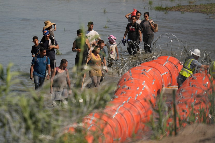 Migrants trying to enter the U.S. from Mexico approach the site where workers are assembling...