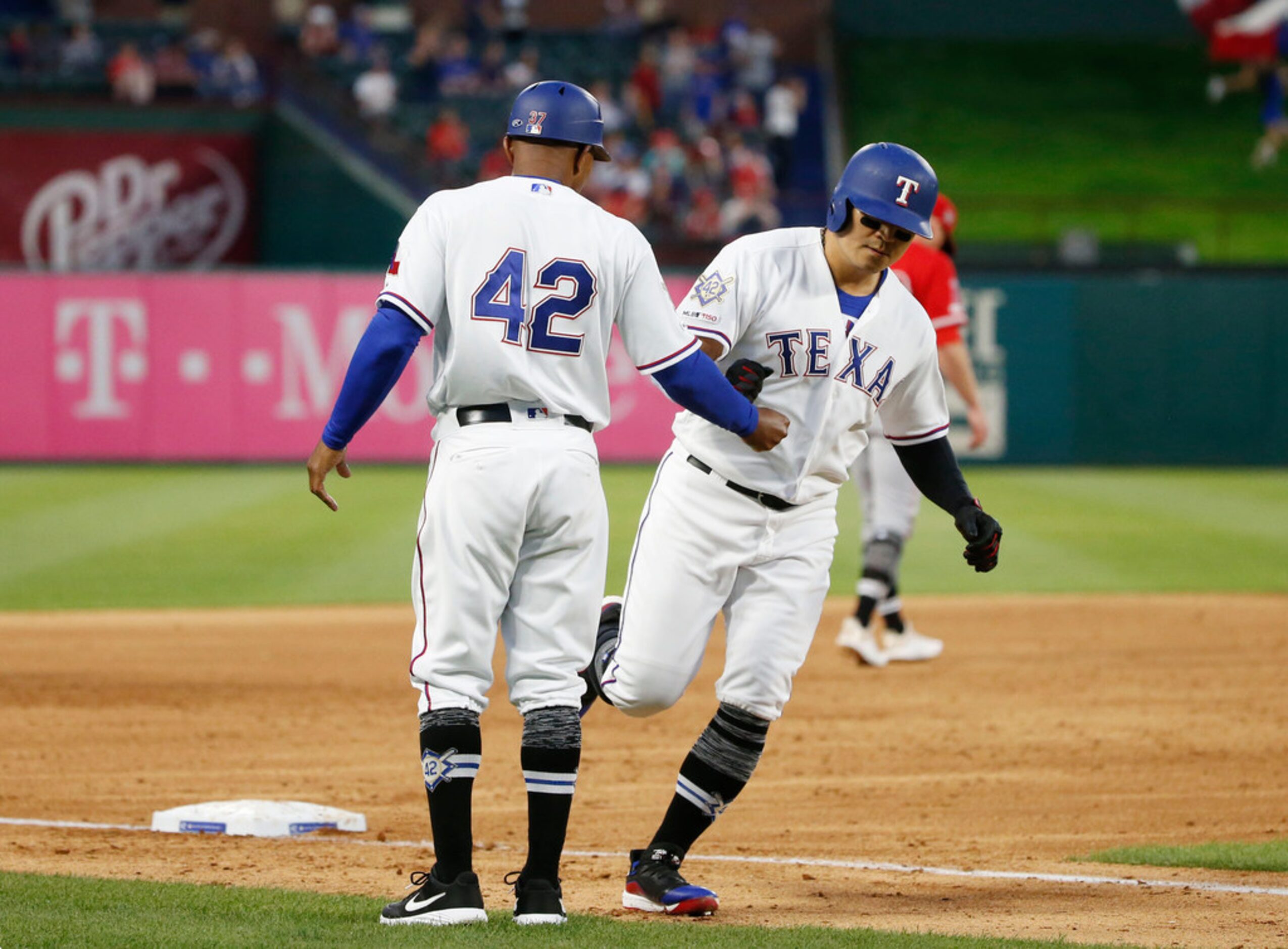 Texas Rangers third base coach Tony Beasley, left, congratulates Shin-Soo Choo, right, who...