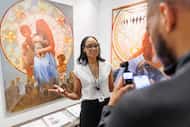Valerie Gillespie, owner of Pencil on Paper Gallery, speaks in front of two paintings by...
