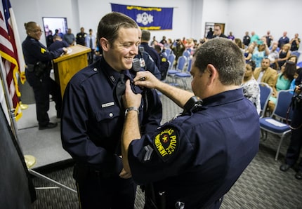 New Dallas police Officer Zachary Jones has his badge pinned on by his father, Dallas police...