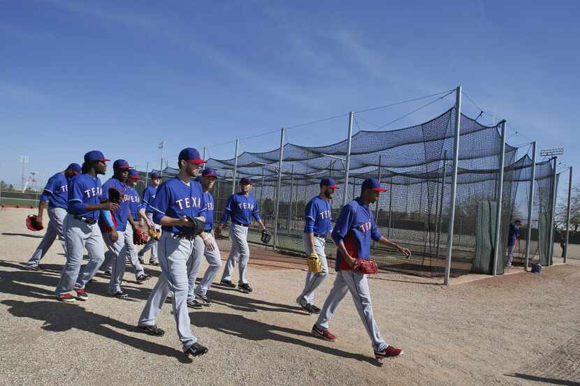 Texas Rangers pitchers make their way past the batting cages on their way to another field...