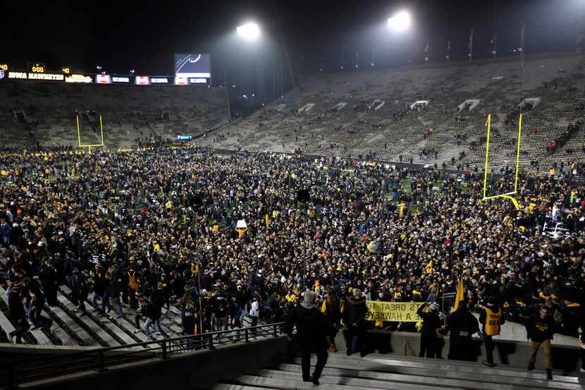 Iowa fans celebrate on the field after an NCAA college football game against Ohio State,...