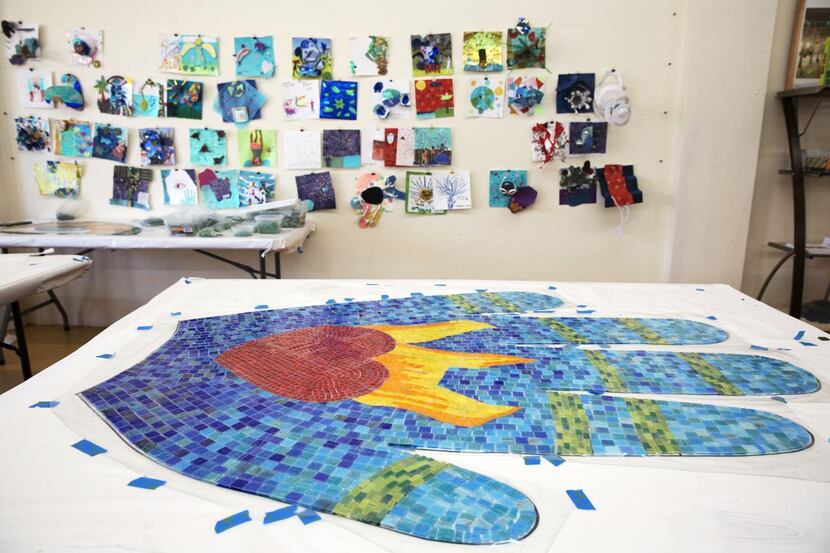 
A completed mosaic hand rests in front of the original inspiration for a 17-foot-tall...