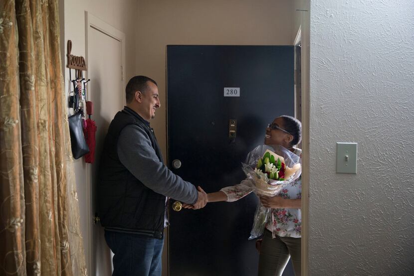 Syrian refugee Abdullah Al Khamis, left, greets guest Leslie Gomez at his front door at a...