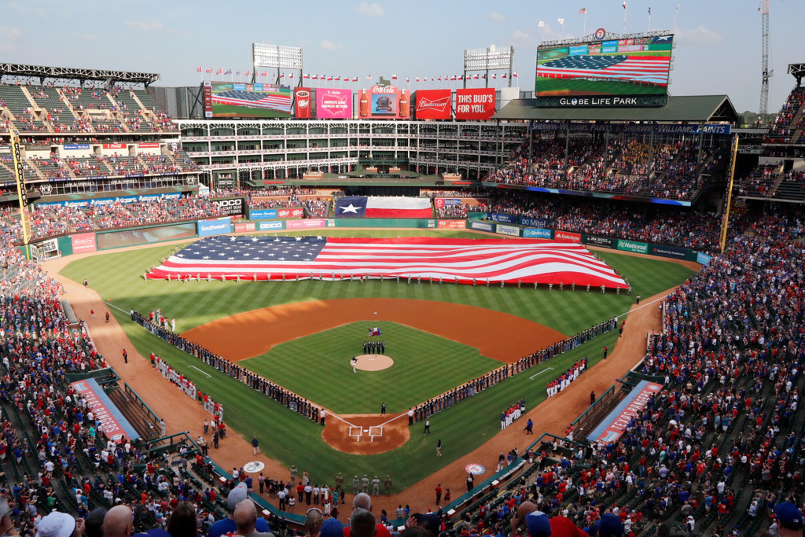 The Los Angeles Angels, Texas Rangers and 150 U.S. Air Force recruits stand on the field as...