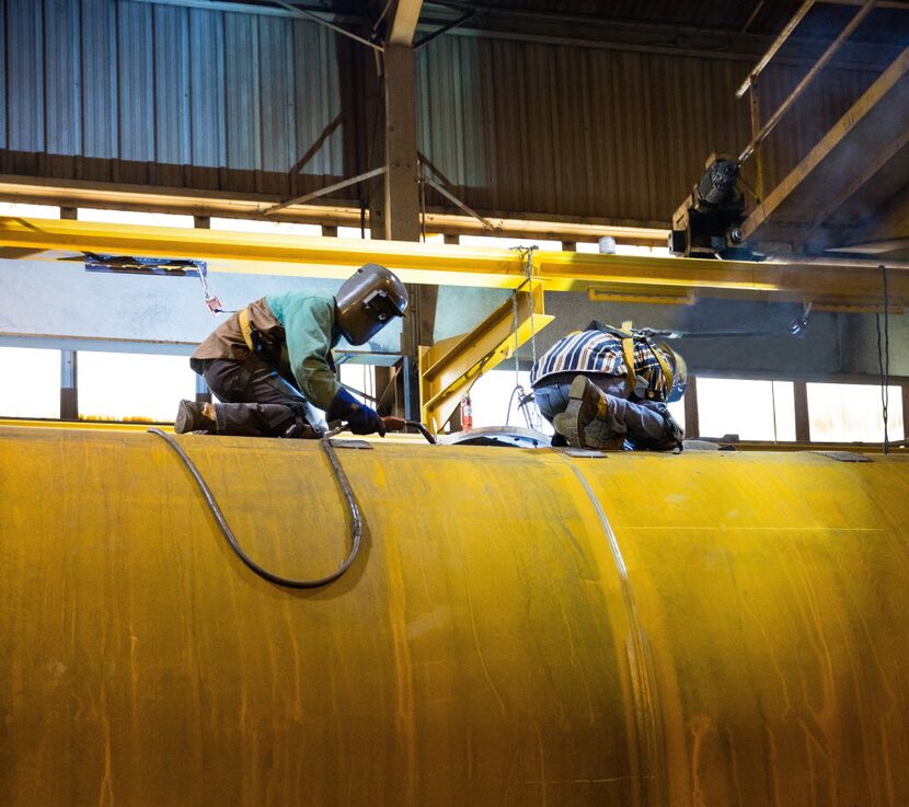 Welders for Dallas-based Trinity Industries work on a crude oil tank car at the company's...