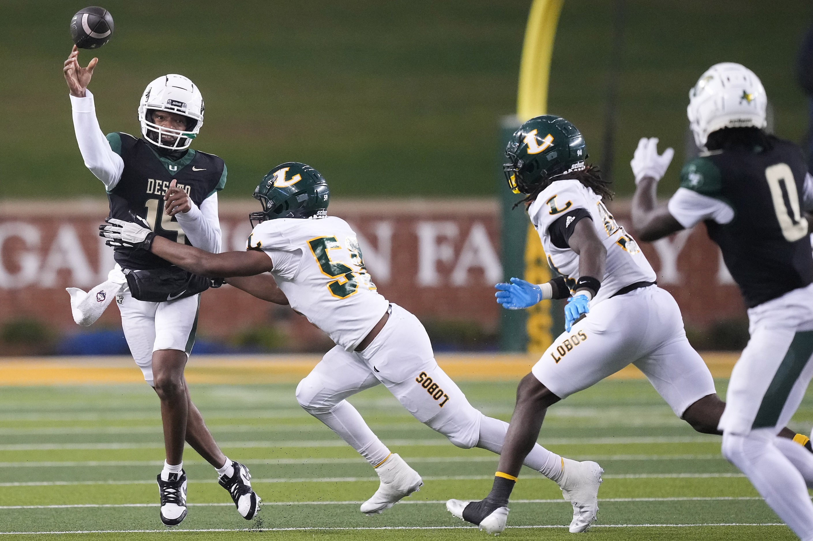 DeSoto quarterback Legend Howell (14) throws a pass intended for running back Myson...