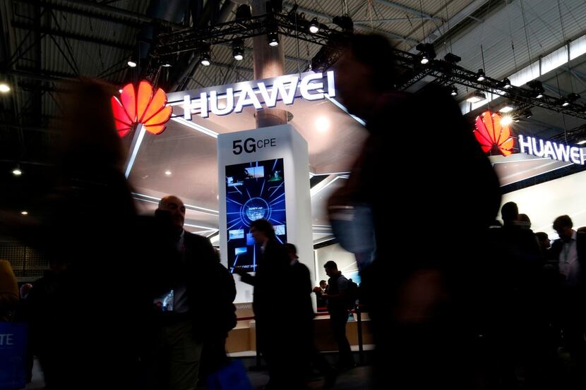 People walk by the Huawei stand at the Mobile World Congress (MWC), the world's biggest...