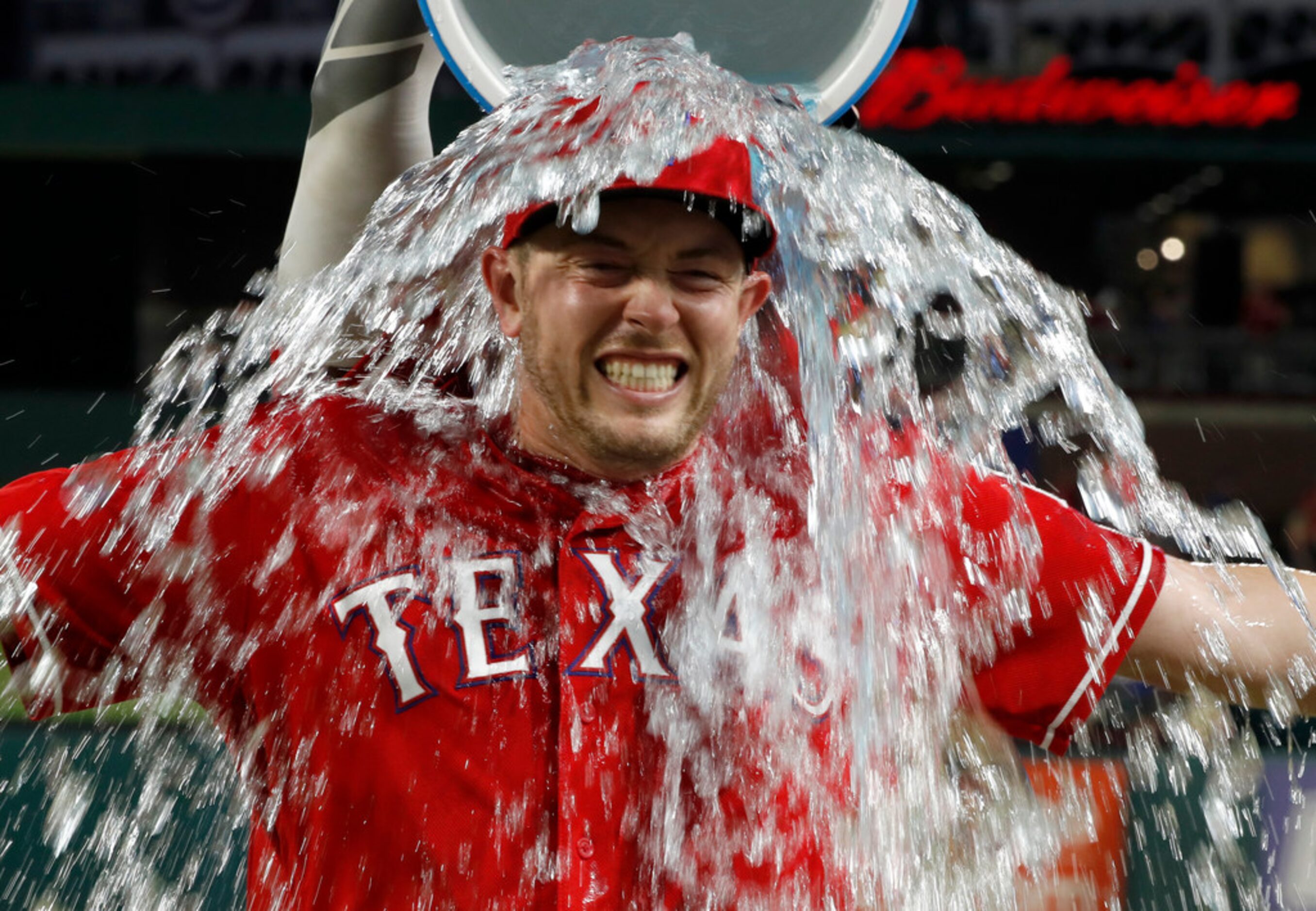 Texas Rangers' Adrian Sampson is doused by Elvis Andrus, rear, after the second baseball...