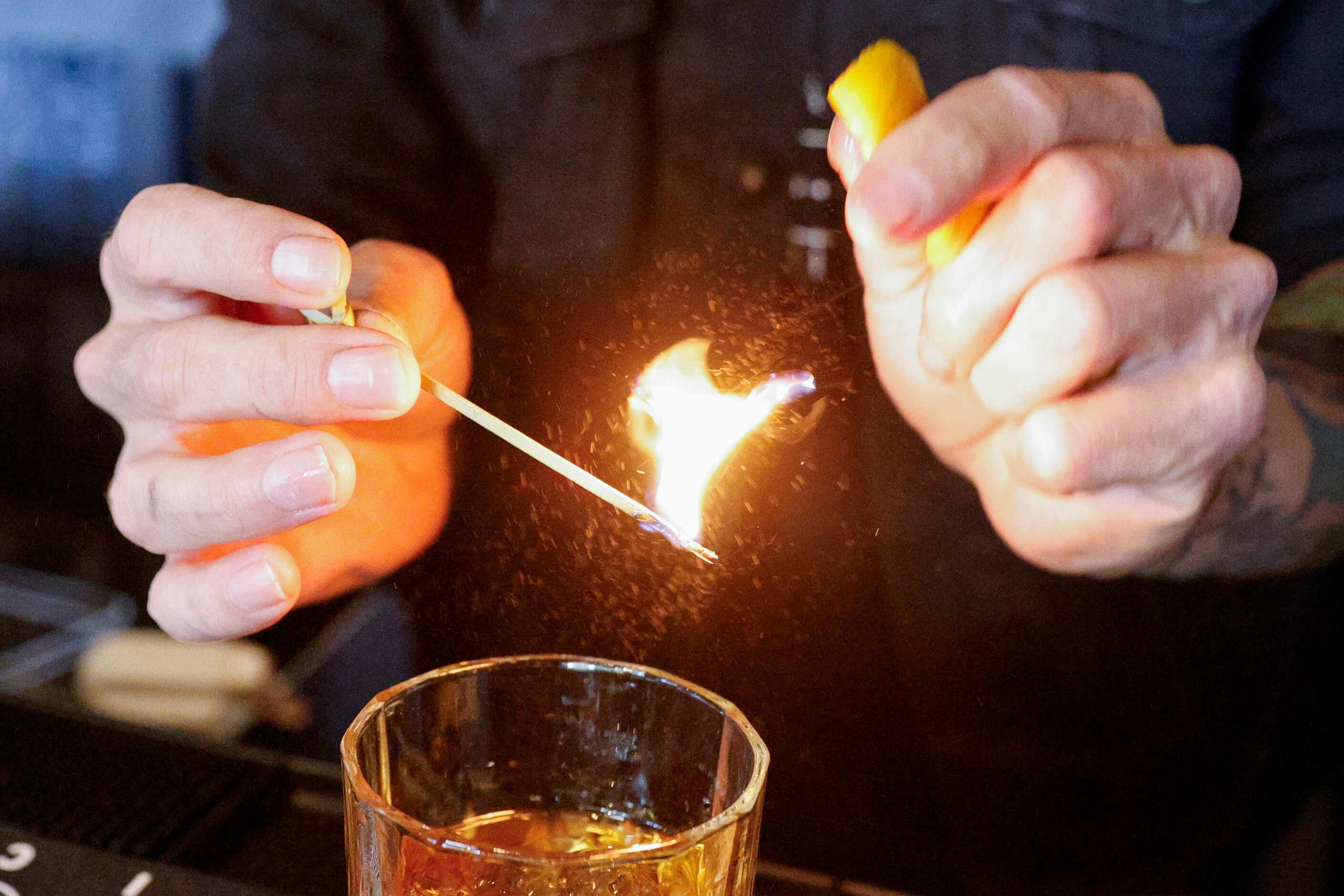 Beverage director Alexander Fletcher flames an orange peel for the 66th old fashioned at...