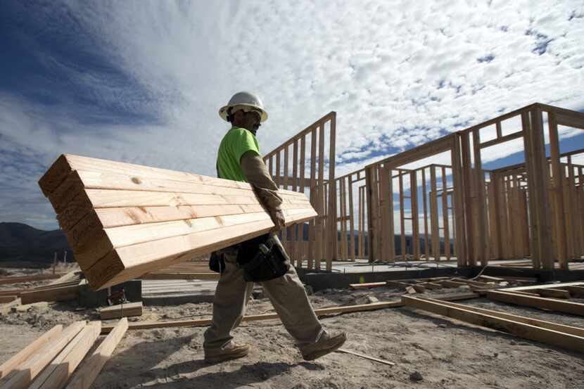 In this Friday, Nov. 16, 2012, photo, construction worker Miguel Fonseca carries lumber as...
