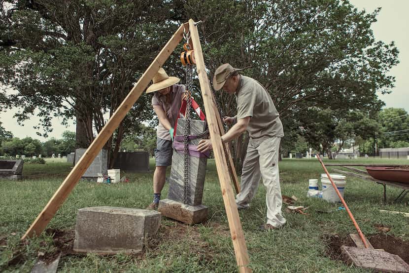 man and woman lift up a gravestone in a cemetery