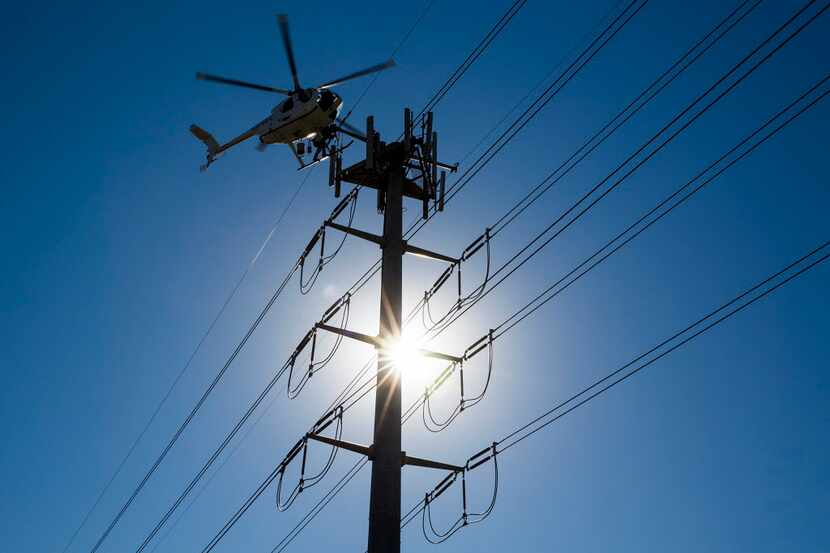  Helicopter linemen for an Oncor contractor work on transmission lines near Royal Lane at...