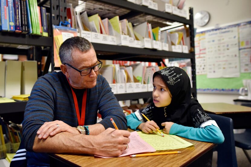 Second grader Bibi Rabialam practices her reading skills with volunteer Douglas Dyment...