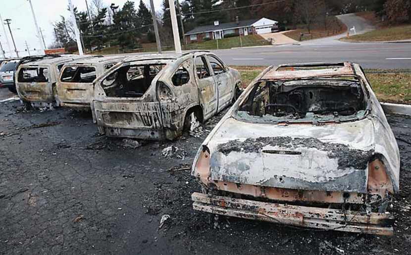 Burned-out cars Tuesday morning in Dellword, Mo., give evidence of the rioting that occurred...