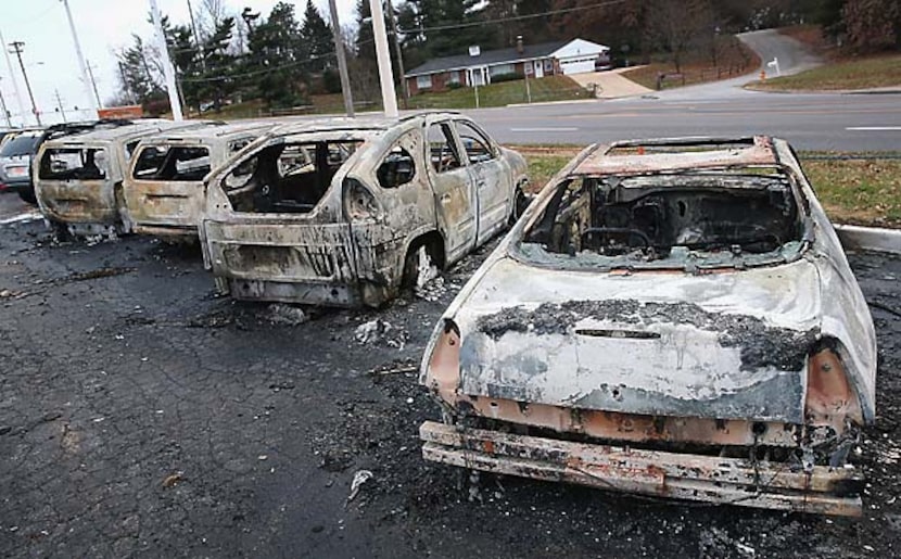 Burned-out cars Tuesday morning in Dellword, Mo., give evidence of the rioting that occurred...